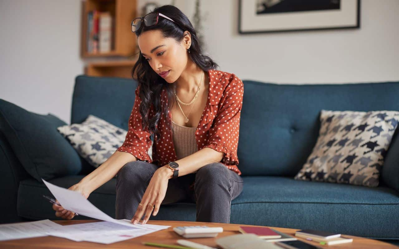 woman reading bill statement on couch