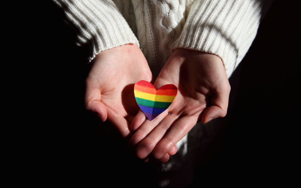 Hands holding a rainbow heart