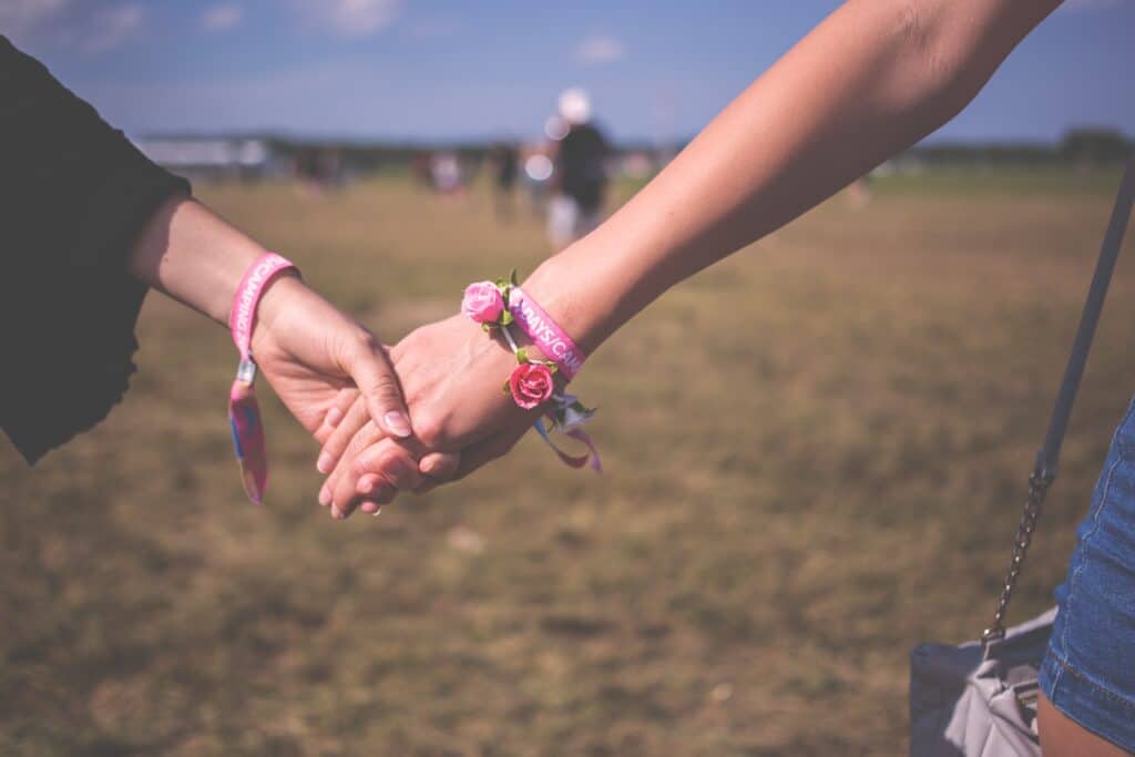 couple holding hands walking in a field